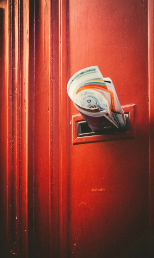 Mail poking out of a brass mail slot in a red door, a literal stand-in for the inbox Kingster Local's email newsletters land in.