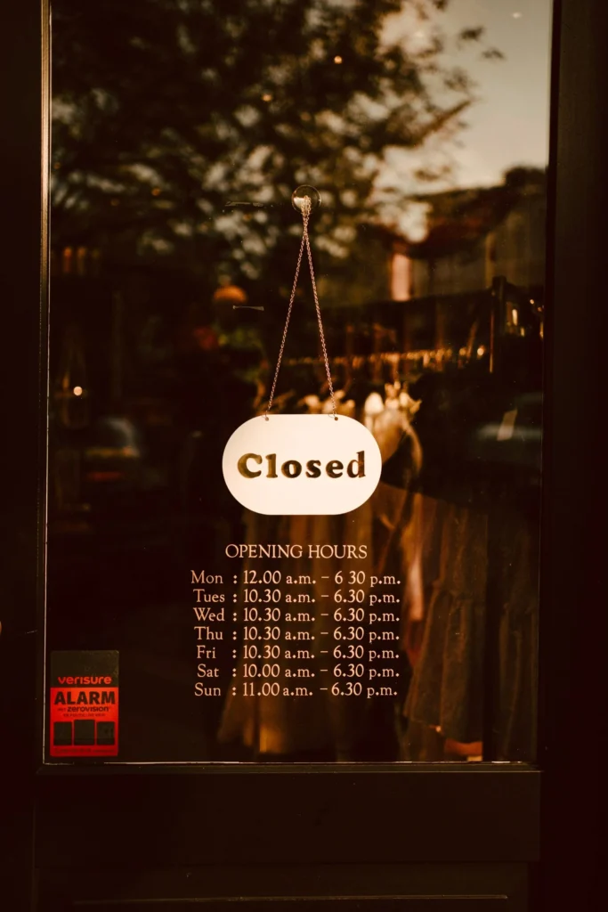 A 'Closed' sign hanging above posted opening hours, the kind of visibility info Kingster Local keeps accurate on Google Business Profile.