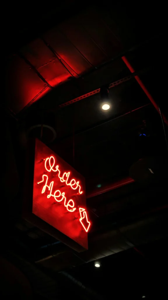 A glowing red neon 'Order Here' sign in a restaurant, standing in for custom ordering features Kingster Local builds into websites.