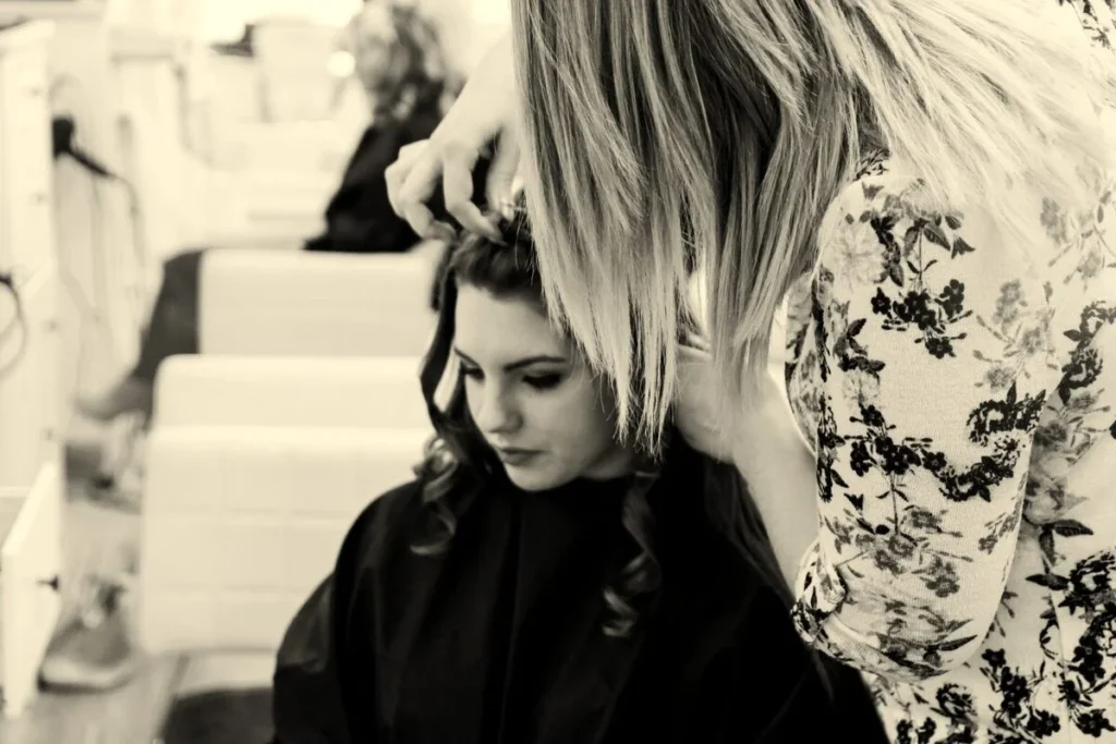 A black-and-white photo of a stylist working through a client's hair, the transformation content that performs well in social ads.