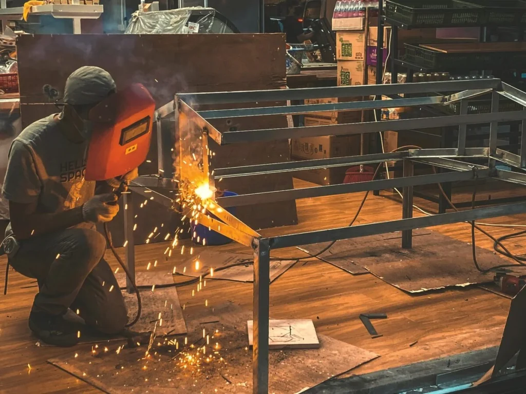 A welder crouched beside a metal frame, sparks flying mid-build, standing in for the groundwork behind a Kingster Local website.